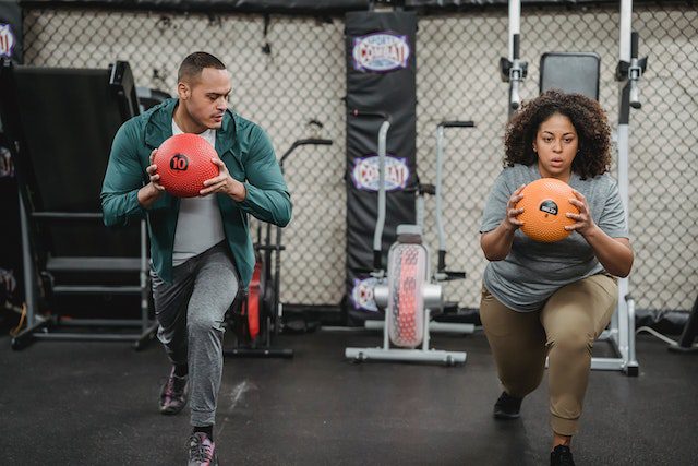 ultiethnic-fit-man-and-obese-woman-with-medicine-ball-doing-lunges-in-sports-club