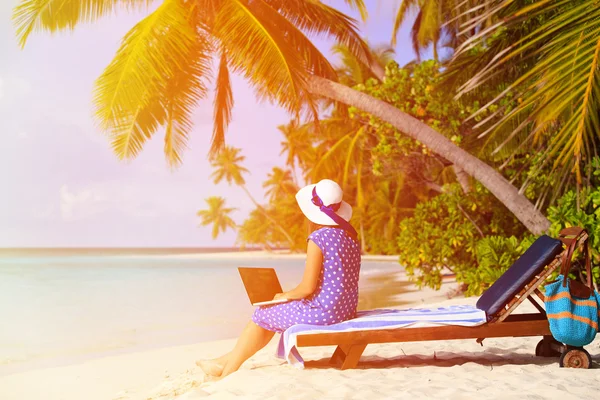 A young lady working remotely on a tropical beach