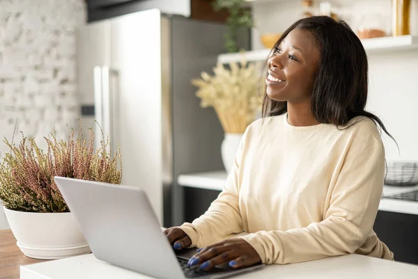 happy freelance woman using a laptop in the kitchen