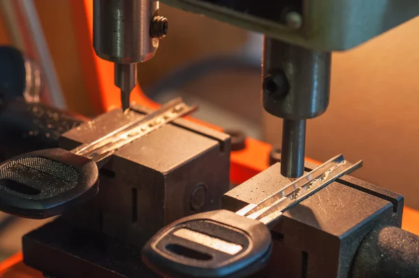 Skilled locksmith cutting key with his machine