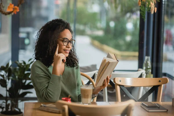 African american woman flipping through pages of book in cafe